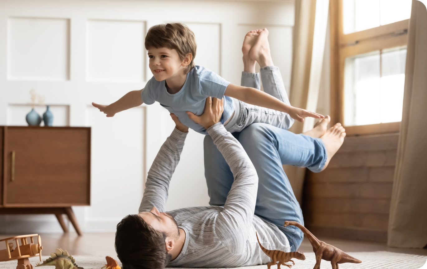 Father playing with child, lifting them up in the air
